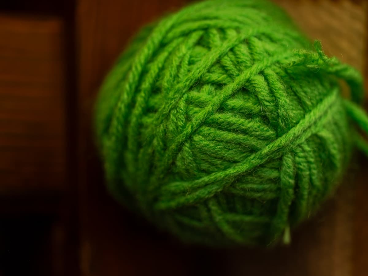 Grøn garnnøgle på træoverflade — garnbanderole og etiket