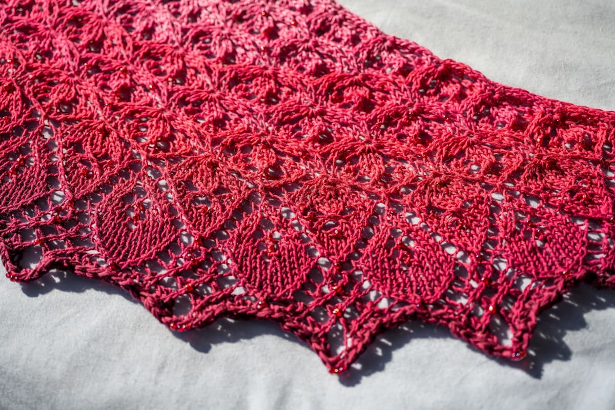 Lacestrikket sjal med åbent bladmønster i rosa garn